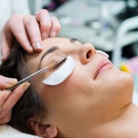 woman having eye lashes tinted in beauty salon