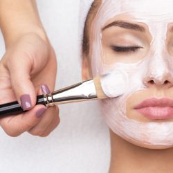 Beautiful young woman receiving facial mask at beauty salon