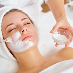 Cleansing procedure. Nice pretty woman lying with her eyes closed while having a cleansing procedure on her face