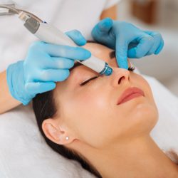 Cleansing procedure. Nice pretty woman lying with her eyes closed while having a cleansing procedure on her face